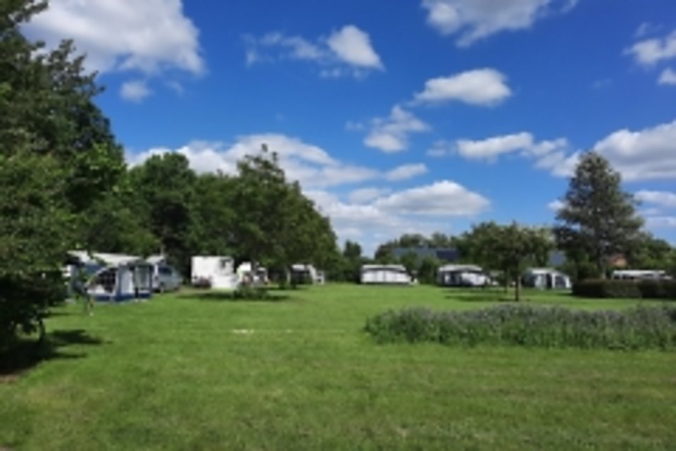 Kampeerveld met caravans onder een blauwe lucht